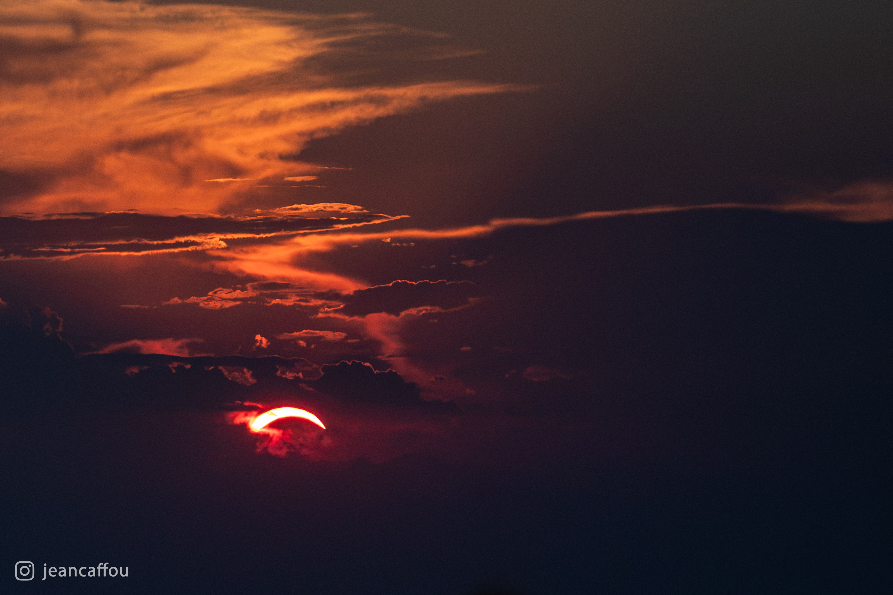 Rdeče srpasto Sonce v plasteh oranžnih in temnih oblakov nad Vremščico.