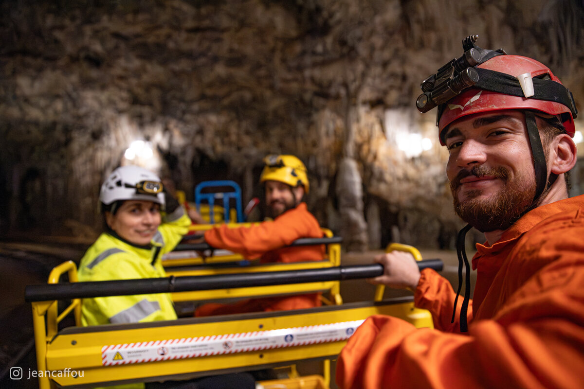 Magdalena Aljančič, Blaž Kogovšek and Raffaele Bruschi sit in the yellow carriages of the Postojna Cave train.